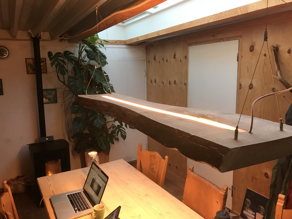 De Slice, hanglamp van massief eiken met lichtlijn, boven een eettafel